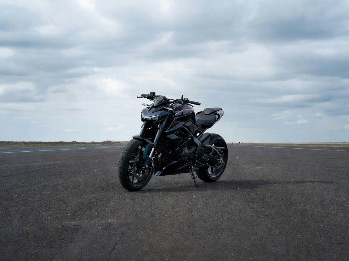 Street-level wide angle capture of a sleek streetfighter motorcycle parked on a clean asphalt proving ground under overcast skies.